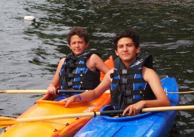 Two young men in kayaks on a body of water.
