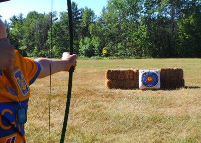 A boy in a yellow shirt is aiming at a target.
