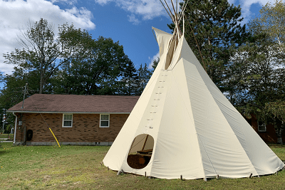A white teepee in front of a house.