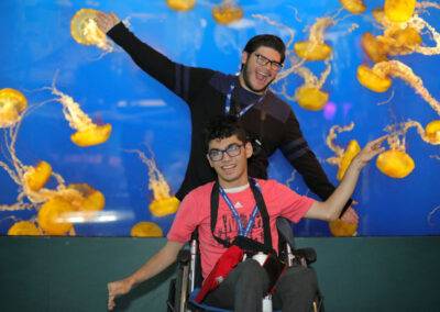 A man in a wheelchair posing in front of jellyfish.