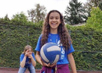 A young girl is holding a volleyball in her hands.