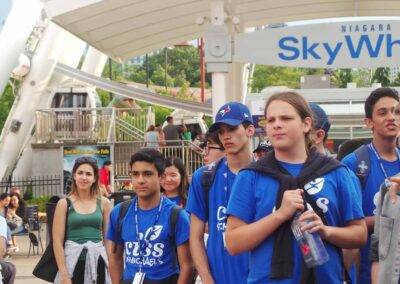 A group of people in blue shirts standing in front of a sky wheel.