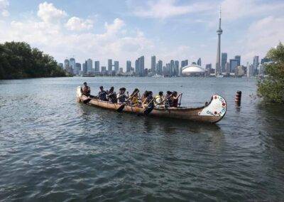 A group of people in a canoe on the water with the cn tower in the background.