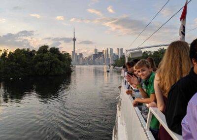 A group of people on a boat looking at the cn tower.