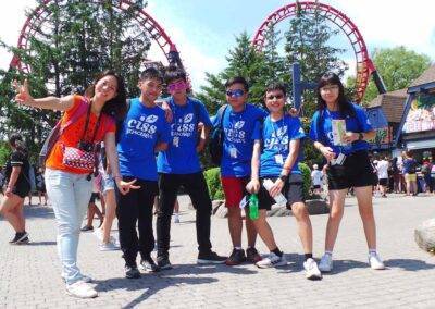A group of people posing in front of a roller coaster.