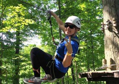 A woman on a zip line in the woods.