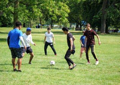 A group of young people playing soccer in a park.