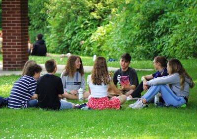 A group of students sitting on the grass in a park.