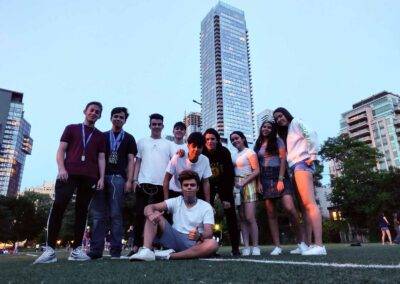 A group of people posing on a soccer field in front of tall buildings.