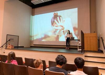 A woman is giving a presentation to a group of people in an auditorium.
