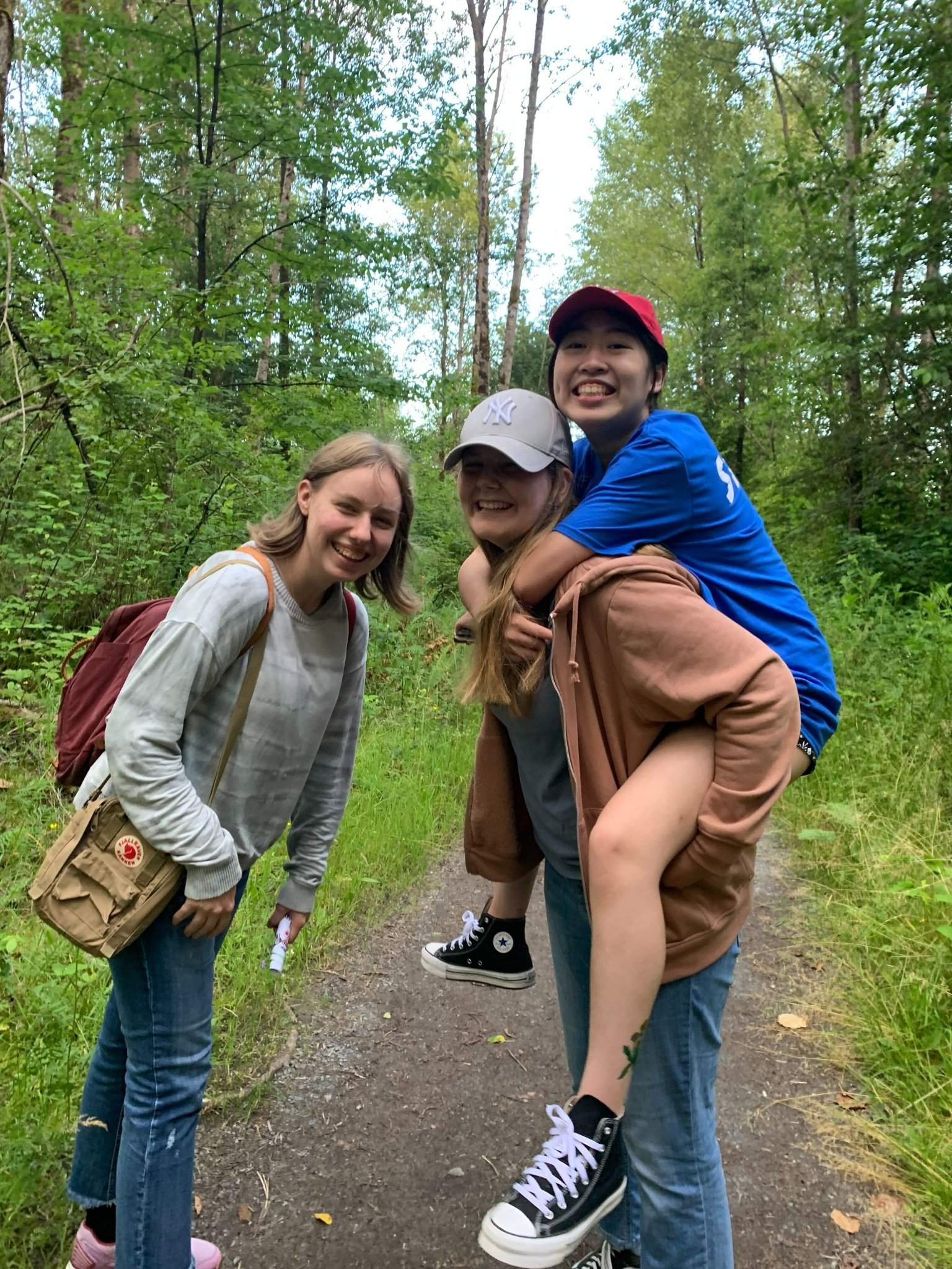 Three people standing on a trail in the woods.