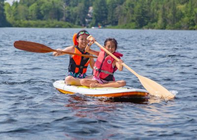 Two people paddling a paddle board on a lake.